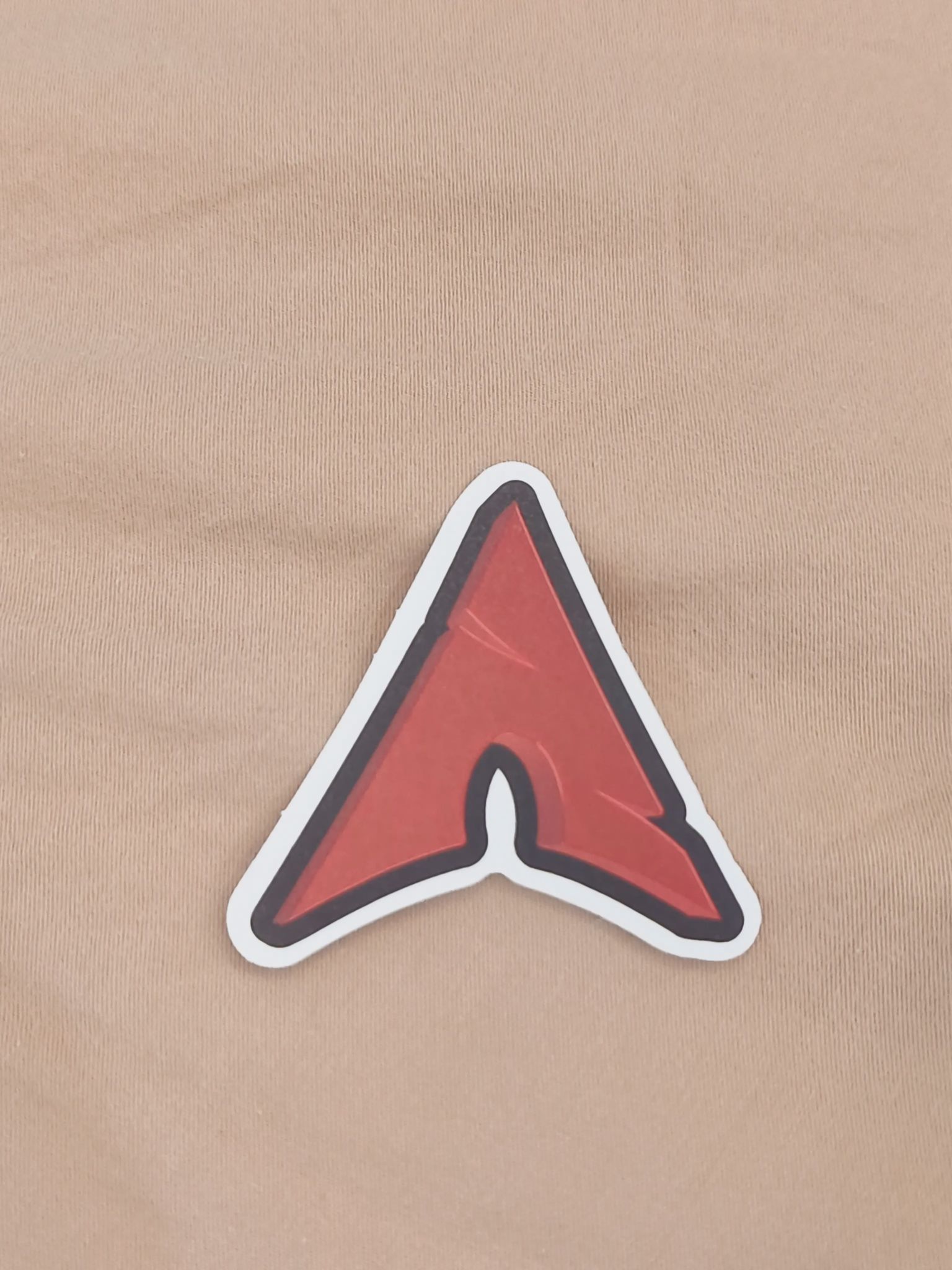 A sticker of a red version of the Arch Linux log